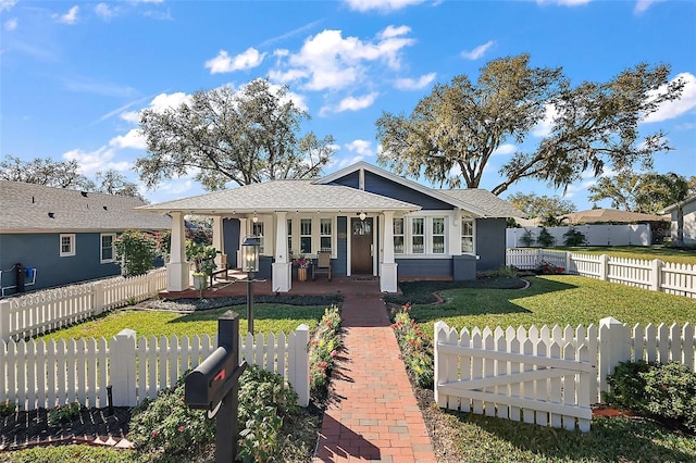 view of front facade featuring covered porch, a front lawn, a fenced front yard, and a shingled roof