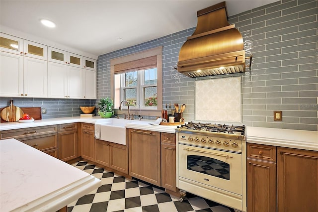 kitchen with glass insert cabinets, custom range hood, stove, and light countertops