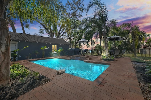 pool at dusk featuring a patio area, fence, and a fenced in pool