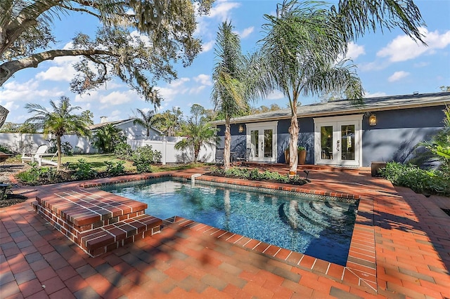 view of pool with french doors, a fenced backyard, and a patio