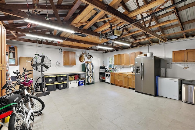 garage featuring fridge, stainless steel refrigerator with ice dispenser, and a garage door opener