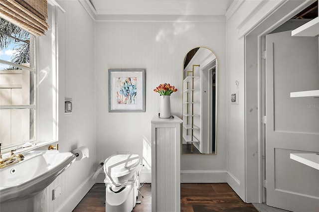 bathroom with toilet, crown molding, a sink, and wood finished floors