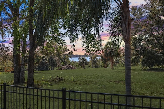 yard at dusk with a water view and fence