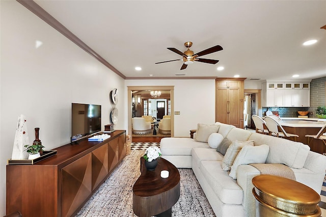 living area featuring ceiling fan with notable chandelier, crown molding, and recessed lighting