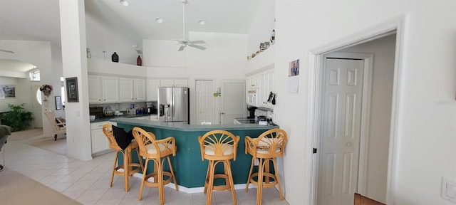 kitchen with a peninsula, a kitchen bar, white cabinets, and stainless steel fridge with ice dispenser