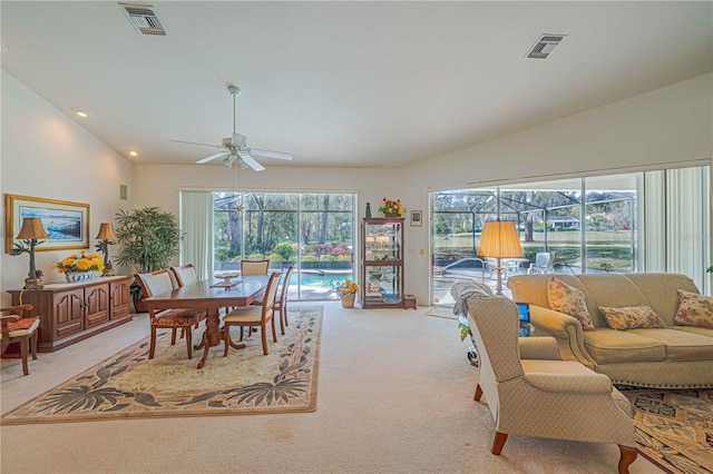 living area featuring light carpet, a sunroom, visible vents, and vaulted ceiling