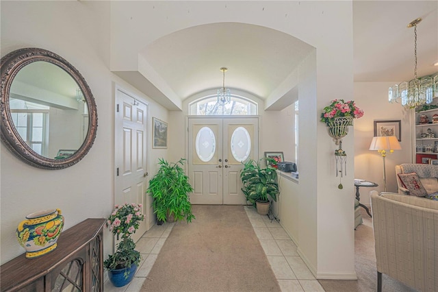 entrance foyer with an inviting chandelier, plenty of natural light, vaulted ceiling, and light tile patterned flooring