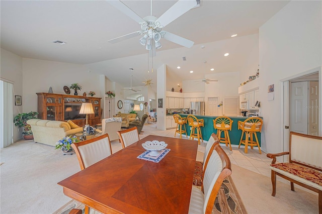 dining area featuring high vaulted ceiling, light colored carpet, a ceiling fan, and light tile patterned flooring