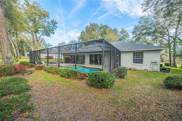 back of house featuring an outdoor pool, a lawn, roof with shingles, a lanai, and stucco siding