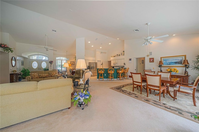 living room featuring light carpet, high vaulted ceiling, visible vents, and a ceiling fan