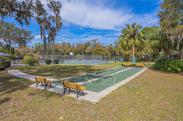 view of community featuring shuffleboard, a lawn, and fence