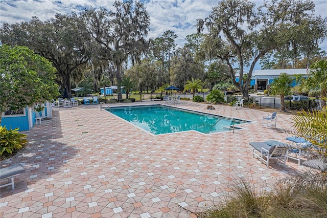 community pool with a patio area and fence