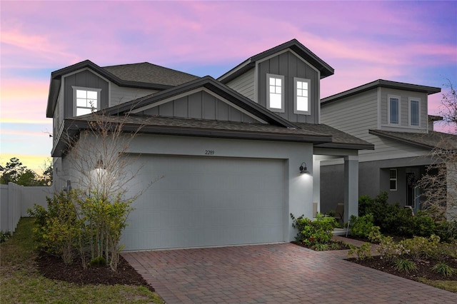 view of front facade featuring a garage, roof with shingles, fence, decorative driveway, and board and batten siding