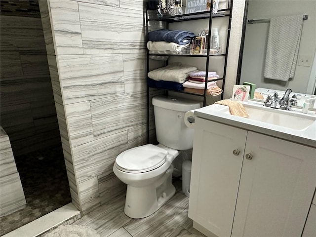 full bath with tile walls, vanity, toilet, and walk in shower