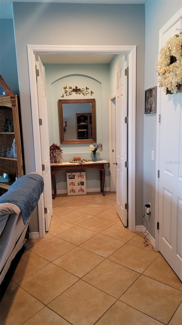 hallway with light tile patterned floors and baseboards