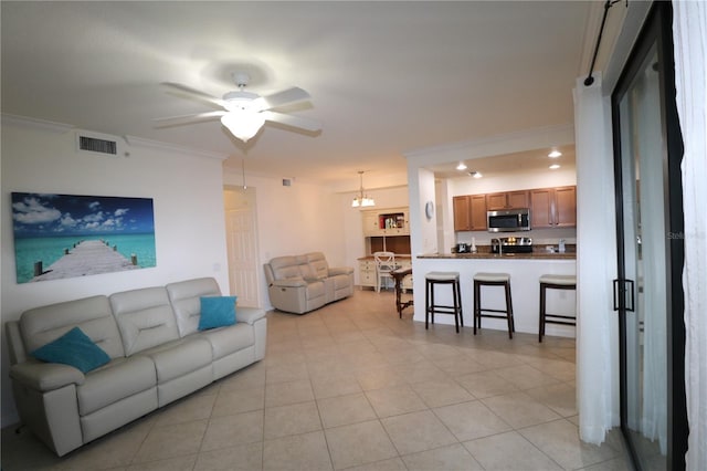 living room with a ceiling fan, light tile patterned flooring, visible vents, and crown molding