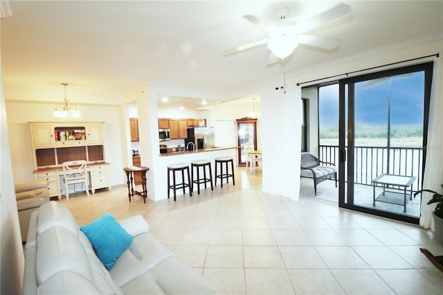 living area with light tile patterned floors, ornamental molding, and ceiling fan with notable chandelier