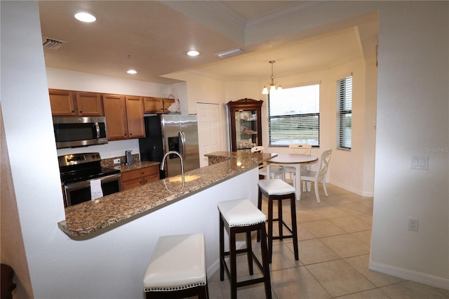 kitchen featuring stainless steel appliances, visible vents, ornamental molding, brown cabinetry, and a kitchen bar