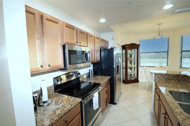 kitchen with light tile patterned flooring, ornamental molding, appliances with stainless steel finishes, dark stone countertops, and decorative light fixtures