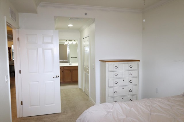 bedroom featuring ensuite bathroom, light colored carpet, a sink, visible vents, and ornamental molding