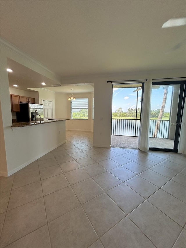 7005 River Hammock Dr Unit 207, Bradenton, FL 34212 - unfurnished living room featuring light tile patterned flooring, a chandelier, recessed lighting, ornamental molding, and a water view