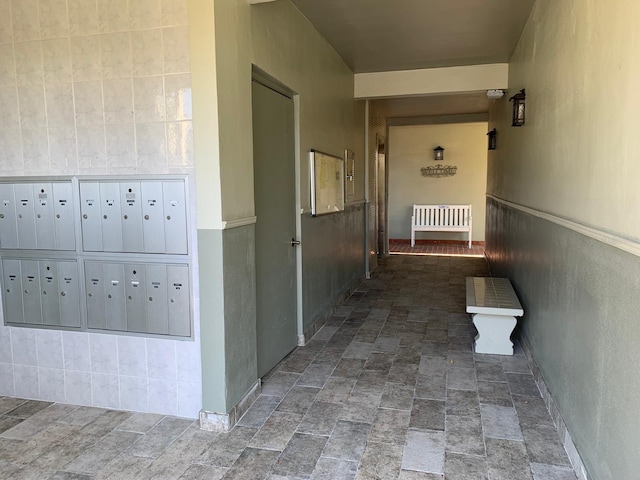 hallway featuring stone finish flooring and mail area