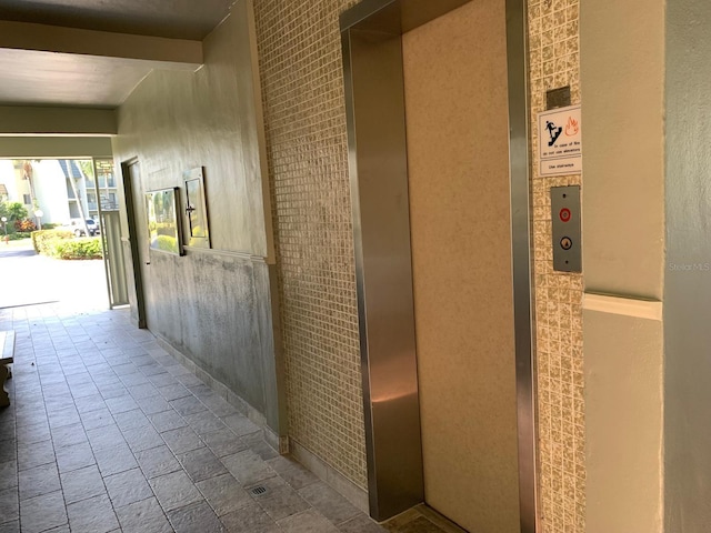 corridor featuring stone tile flooring and elevator