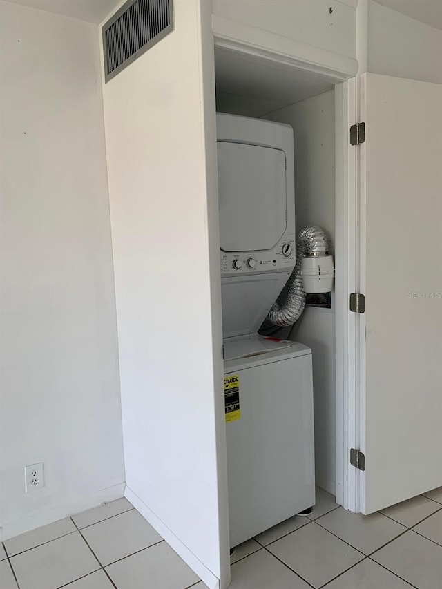 clothes washing area featuring light tile patterned floors, laundry area, stacked washer / dryer, and visible vents