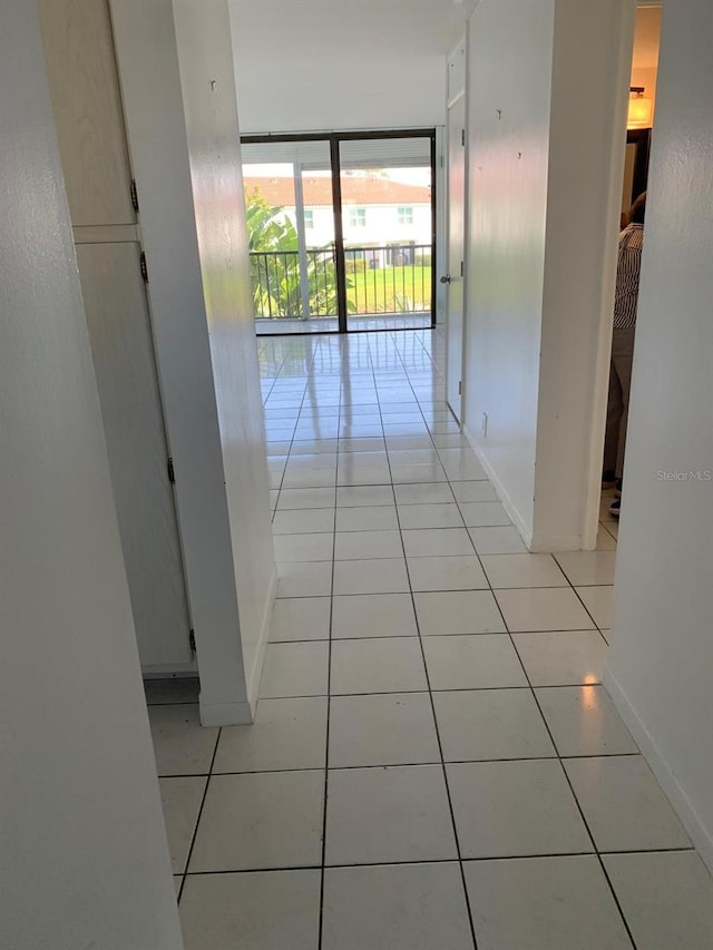 hallway with a wall of windows, baseboards, and light tile patterned floors