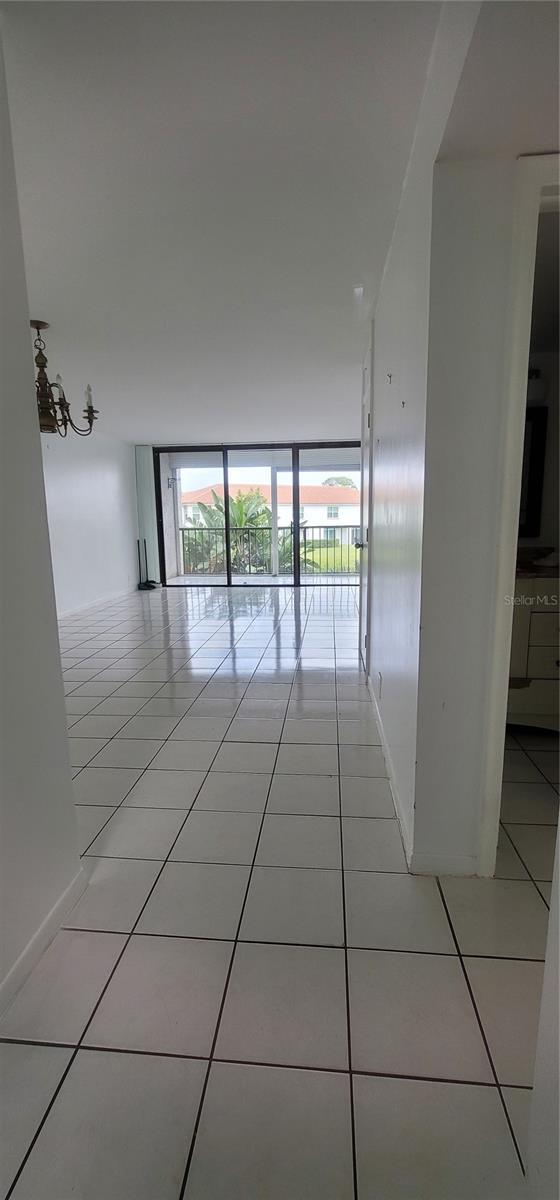 spare room featuring a wall of windows, light tile patterned flooring, and baseboards