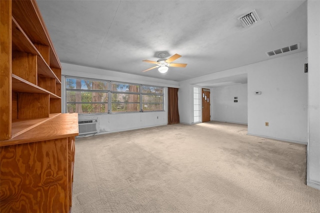 unfurnished living room featuring a ceiling fan, a wall unit AC, visible vents, and light colored carpet