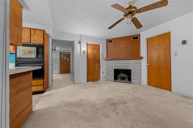 living room with light carpet, a brick fireplace, visible vents, and a ceiling fan