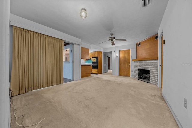 unfurnished living room with light carpet, a fireplace, visible vents, baseboards, and a ceiling fan