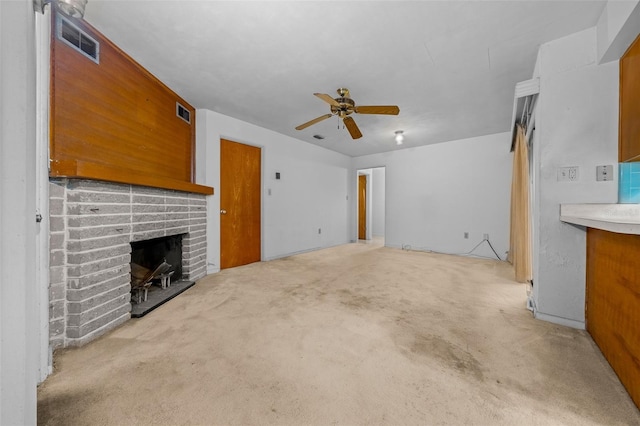 unfurnished living room with light carpet, ceiling fan, a fireplace, and visible vents