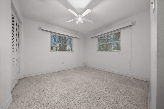 empty room with light speckled floor, ceiling fan, and baseboards