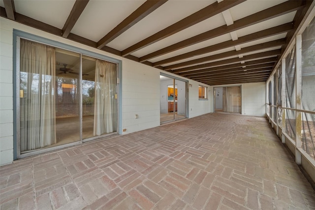 unfurnished sunroom featuring a ceiling fan and beamed ceiling