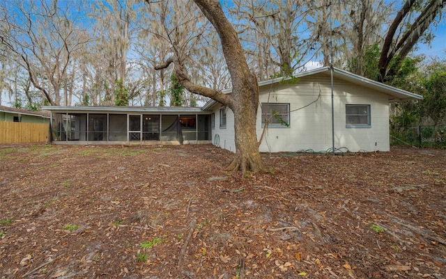 view of front of home with a sunroom, fence, and concrete block siding