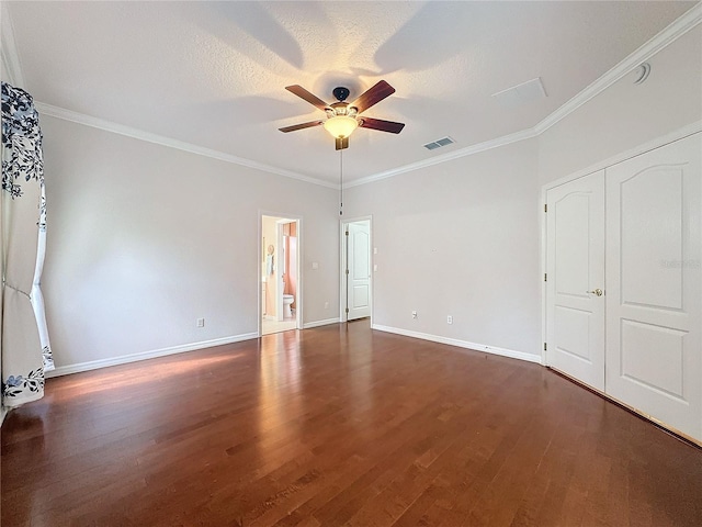 unfurnished bedroom with dark wood-style floors, visible vents, crown molding, and baseboards