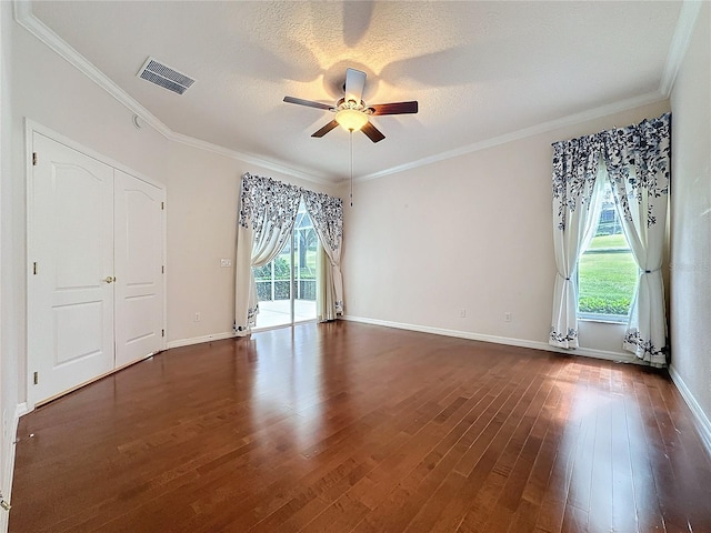 interior space featuring dark wood-style floors, visible vents, plenty of natural light, and crown molding