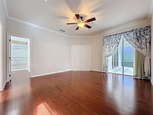 spare room with crown molding, visible vents, dark wood finished floors, and baseboards