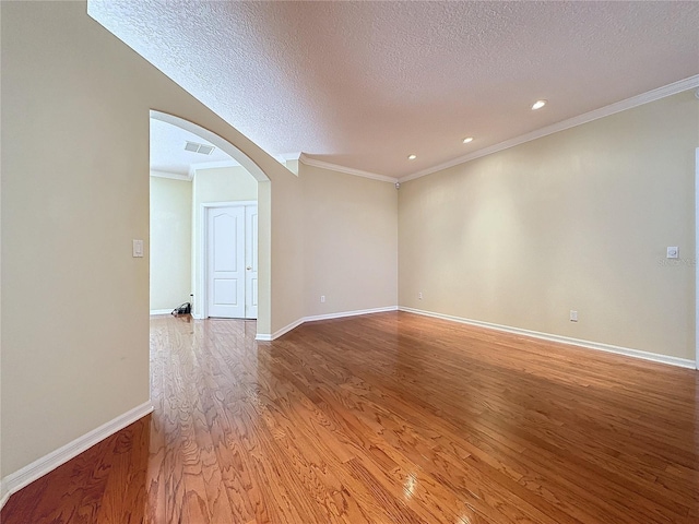 spare room with visible vents, arched walkways, baseboards, a textured ceiling, and light wood-style floors