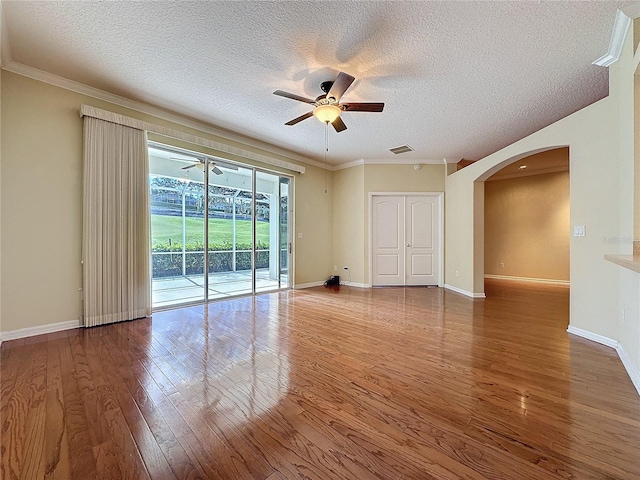 spare room with visible vents, arched walkways, ceiling fan, and hardwood / wood-style floors