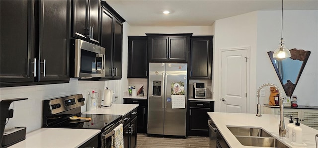 1723 Happiness Row, Kissimmee, FL 34744 - kitchen featuring dark cabinets, a sink, light countertops, appliances with stainless steel finishes, and pendant lighting