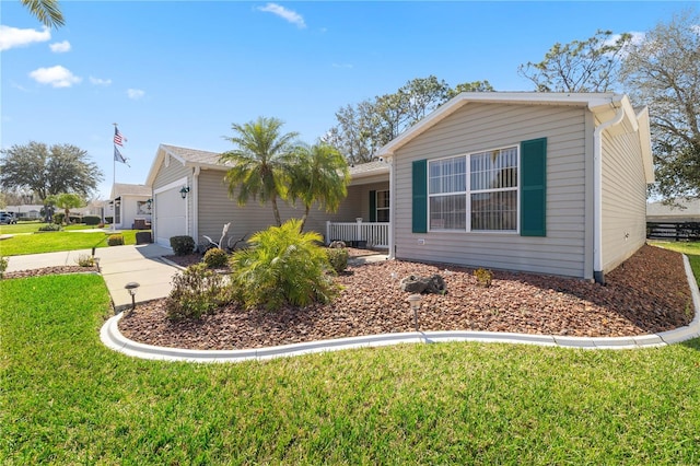 view of front of house with a garage, a front yard, concrete driveway, and a porch