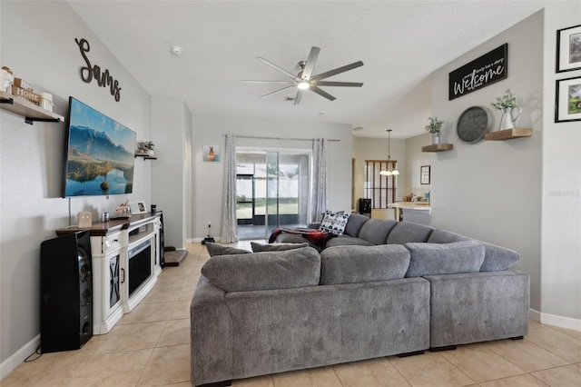 living room with light tile patterned flooring, baseboards, and ceiling fan with notable chandelier