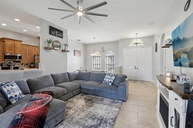 living area with light tile patterned floors, ceiling fan with notable chandelier, visible vents, and recessed lighting