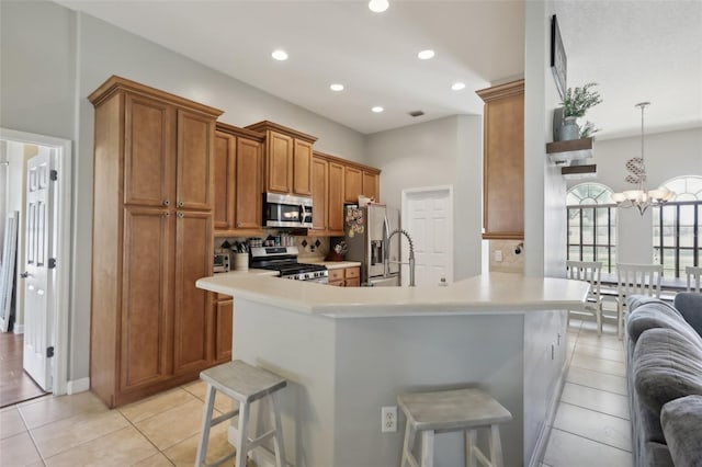 kitchen featuring light tile patterned floors, appliances with stainless steel finishes, brown cabinetry, and a breakfast bar