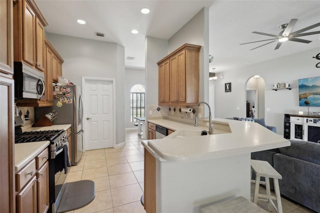 kitchen featuring light tile patterned floors, arched walkways, stainless steel appliances, a sink, and open floor plan