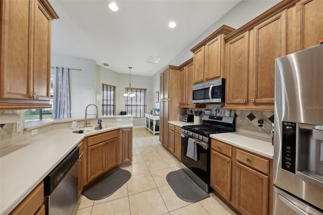 kitchen with stainless steel appliances, brown cabinets, a sink, and light tile patterned floors