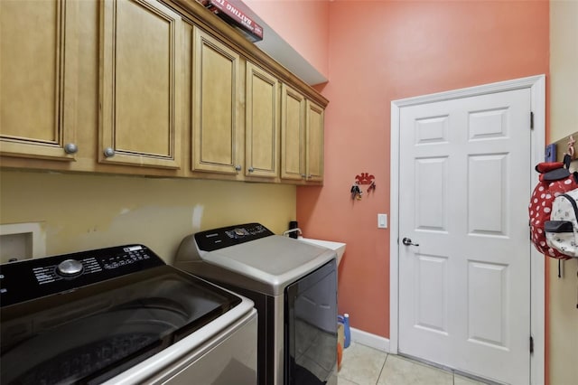 washroom featuring cabinet space, baseboards, washer and clothes dryer, and light tile patterned flooring